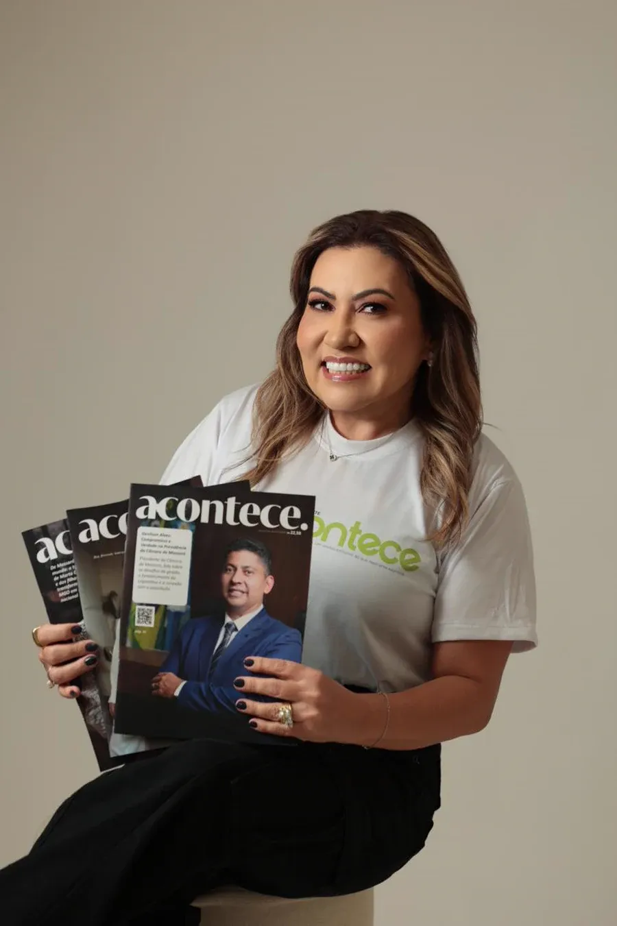 Assinante do Clube Acontece sorrindo, segurando várias edições impressas da Revista Acontece